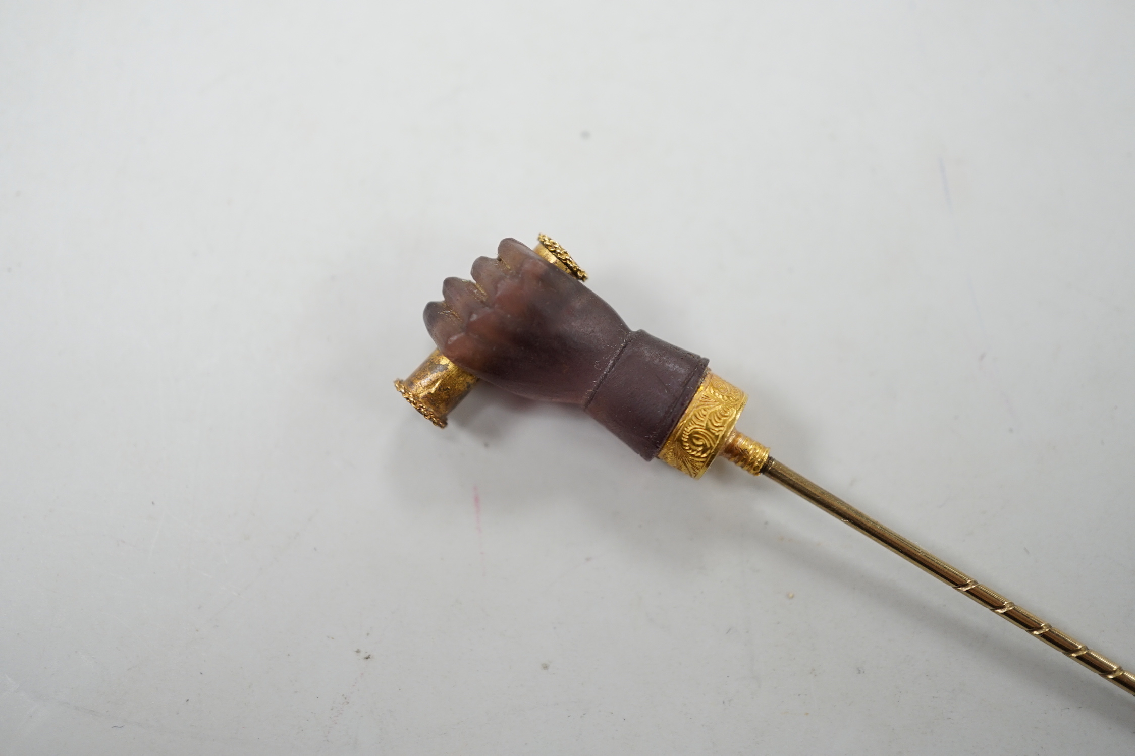 A cased 19th century yellow metal and amethyst glass? set Stanhope stick pin, modelled as hand holding a spyglass, 85mm, the lens depicting the bust of military? gentleman.
